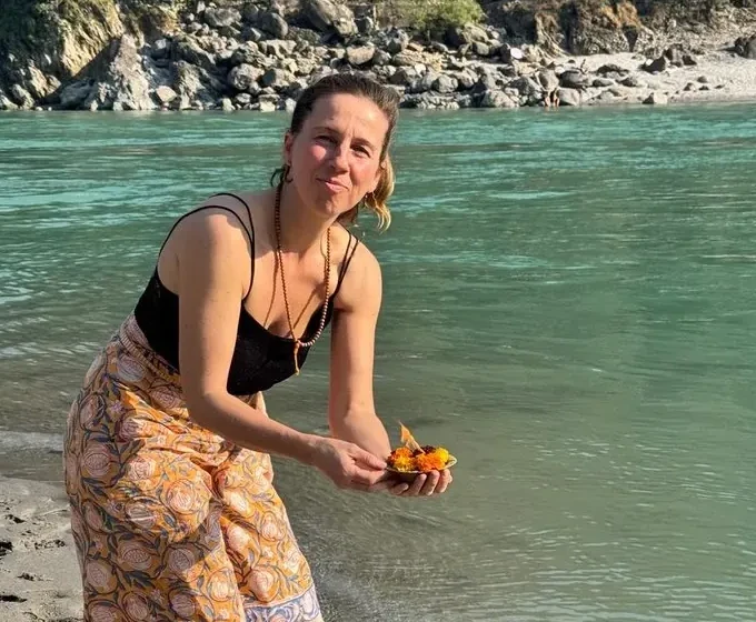 Alicia de la Villa junto a un río, sosteniendo una ofrenda de flores